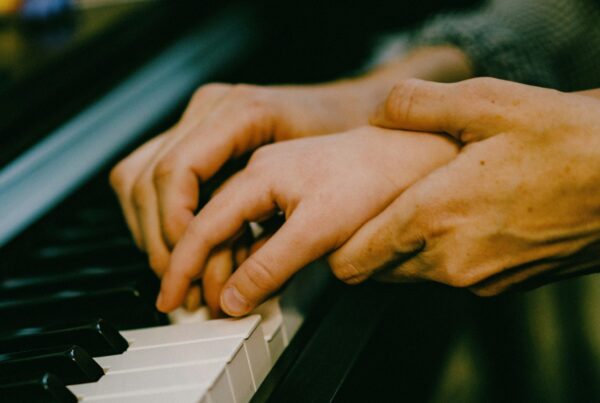 hand helping smaller hand to play piano